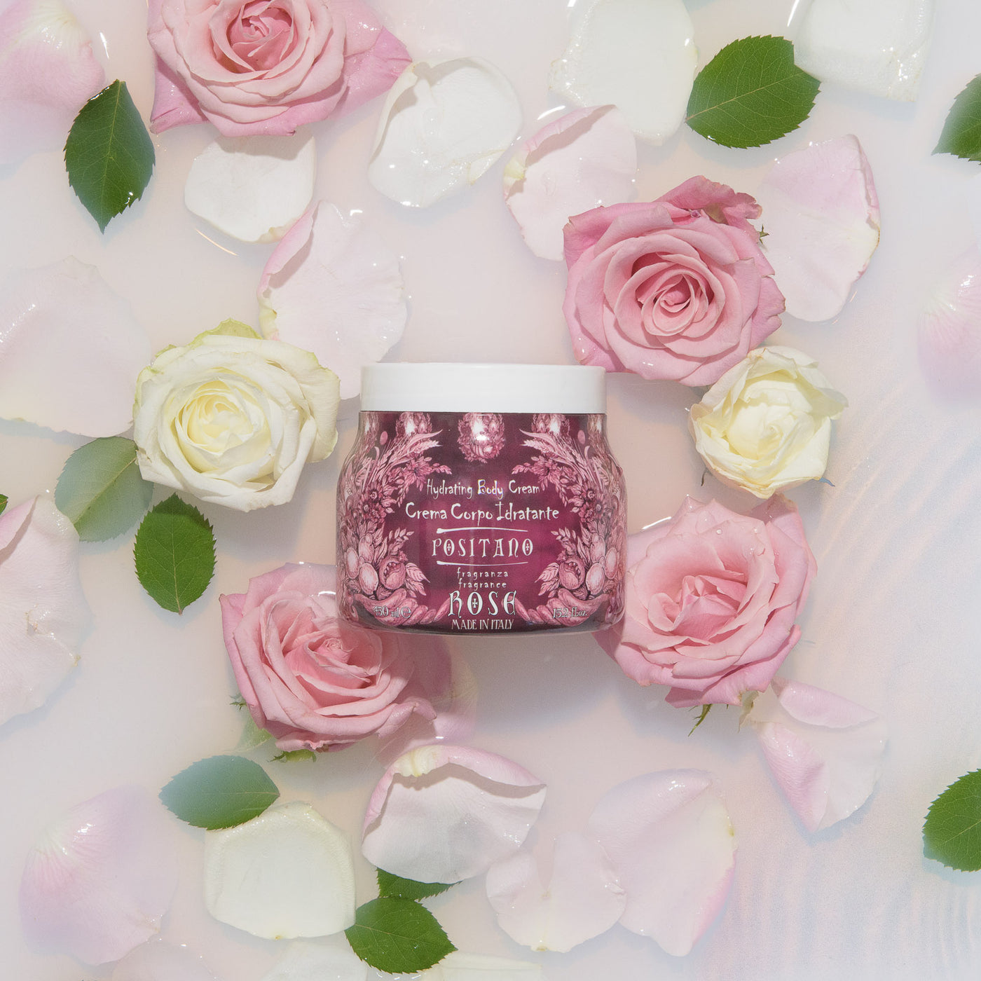 Crema corpo della linea Positano Rose delle Maioliche di Rudy adagiata su un fondo di latte e rose.